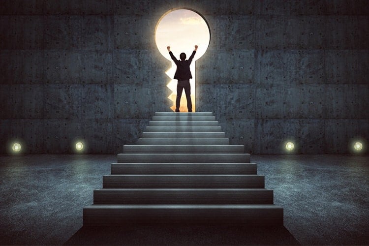 Man standing at top of stairs looking through keyhole